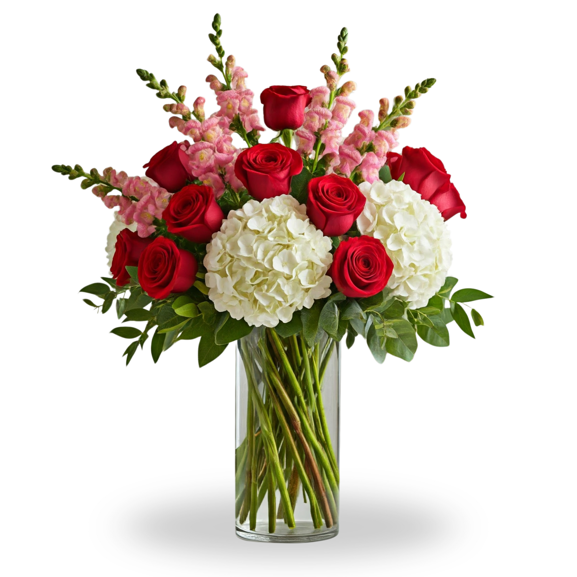 A tall clear glass vase featuring deep red roses, pink snapdragons, and white hydrangeas, accented with lush greenery in a luxurious arrangement.