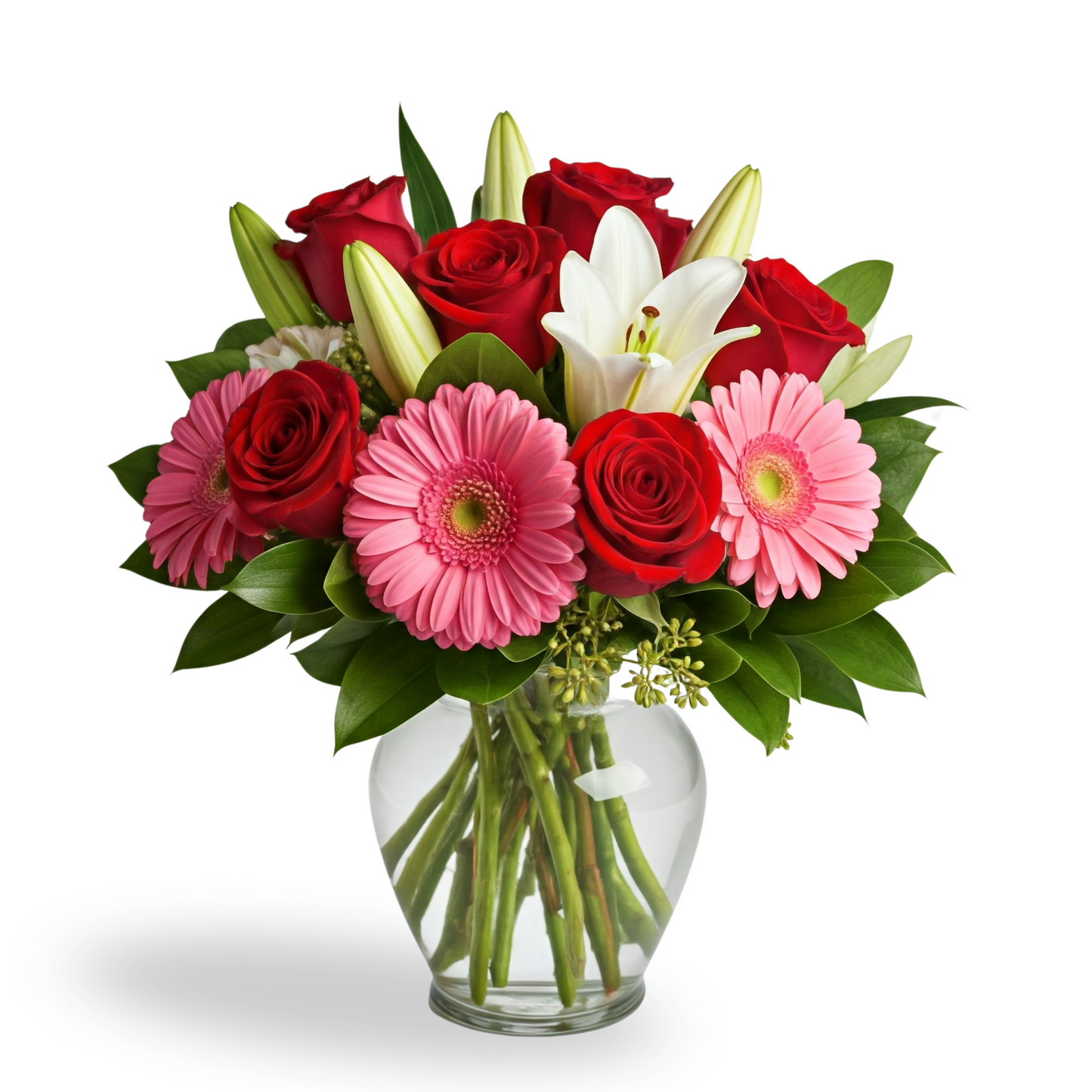 A vibrant bouquet featuring red roses, pink gerbera daisies, and white lilies arranged in a clear cylindrical glass vase, accented with lush greenery.