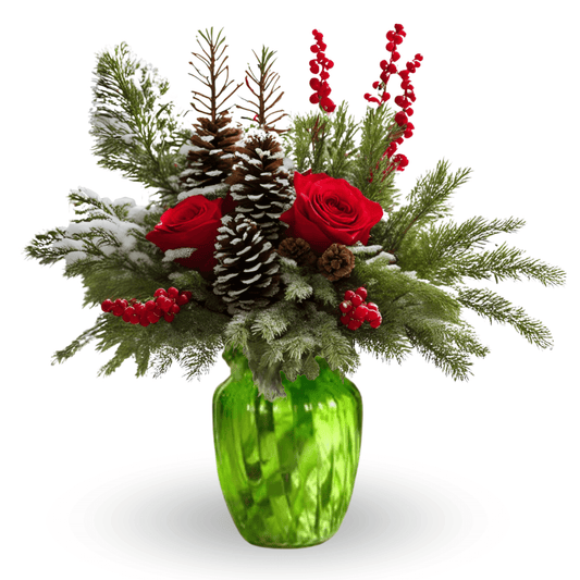 A Christmas floral arrangement featuring red roses, frosted pinecones, berry branches, and holiday greenery in a green glass vase, set against a cozy winter window backdrop.